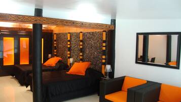 Relax in a stylish room with a large bed, black-framed mirror, and comfortable armchair.