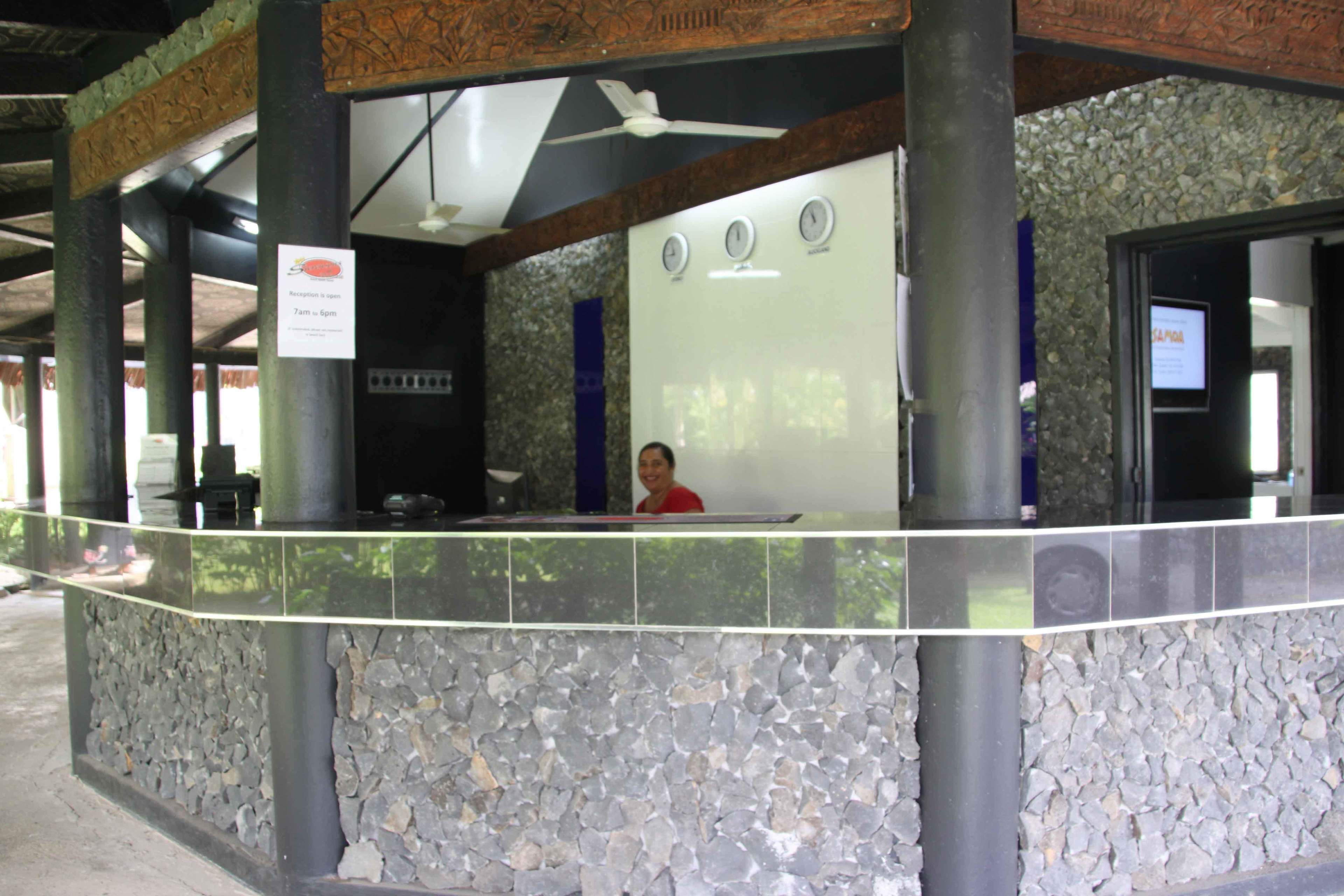 A reception area with a stone wall, a reception desk, and a ceiling fan.