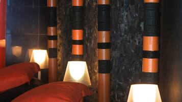 A hotel room with a bed, pillows, a lamp, and decorative pillars.