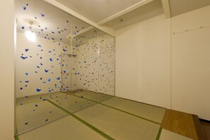 Una habitación con suelo de tatami, una puerta corredera con calcomanías de mariposas azules y una plataforma de madera en la entrada.