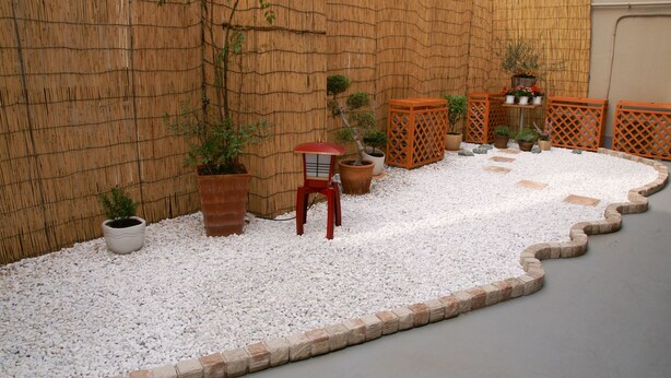 A garden with white gravel paths, bamboo walls, and various potted plants. - Hostel Zen (Yokohama)