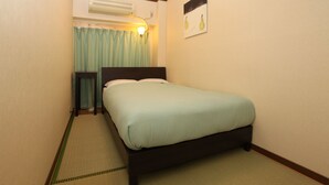 A single bed in a room with a headboard, a bedside table, and a wall-mounted air conditioner. - Hostel Zen (Yokohama)