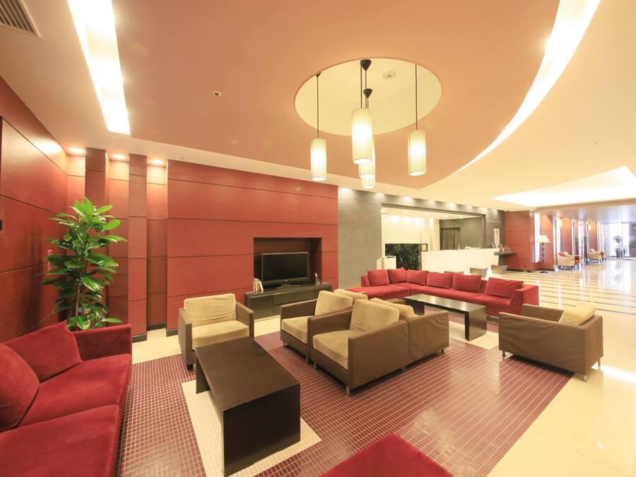 A spacious lobby with multiple seating areas, a flat-screen TV, and a large potted plant.