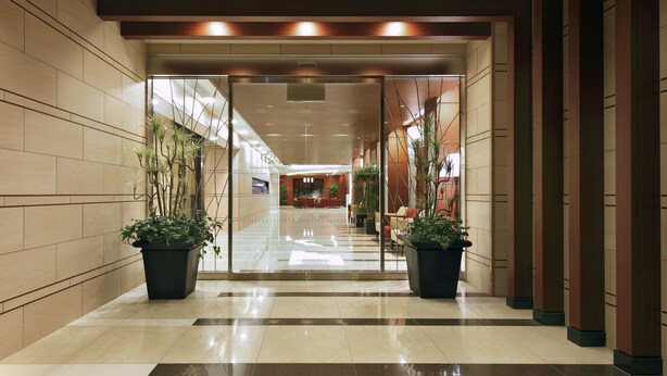 A modern hotel lobby with a check-in desk, potted plants, and a glass partition. - Daiwa Roynet Hotel Sakaihigashi (Sakai)