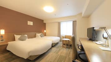 A hotel room with two beds, a desk with a computer, a TV, and a small table.