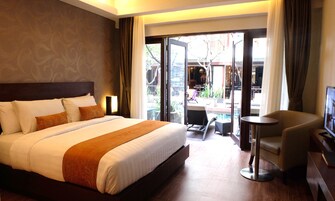 Quarto de hotel com uma cama grande, uma mesa, uma cadeira e vista para a área externa.