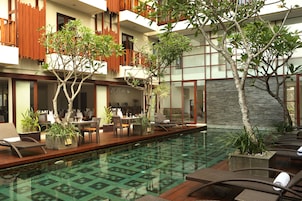 Una piscina al aire libre, sombrillas, sillones reclinables de piscina