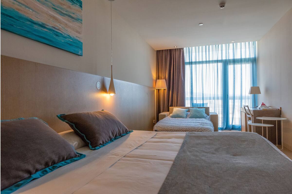 Ein Hotelzimmer mit zwei Betten, einem Schreibtisch und einem Stuhl.
