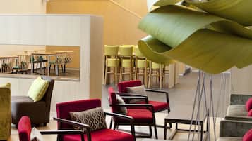 A spacious lobby with modern furniture, a large mirror, and a unique green sculpture.