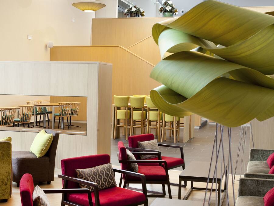A spacious lobby with modern furniture, a large mirror, and a unique green sculpture.