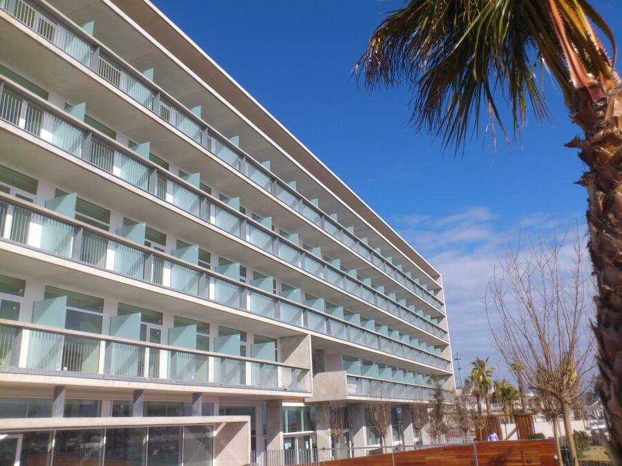Un hotel de varios pisos con un diseño arquitectónico moderno, que cuenta con balcones en cada planta y ventanas amplias.