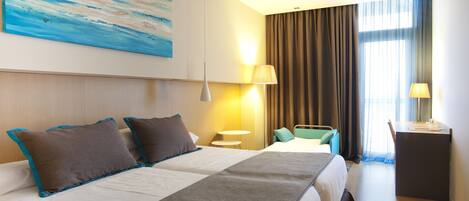 A hotel room with two beds, a desk, a chair, a lamp, and a painting on the wall.