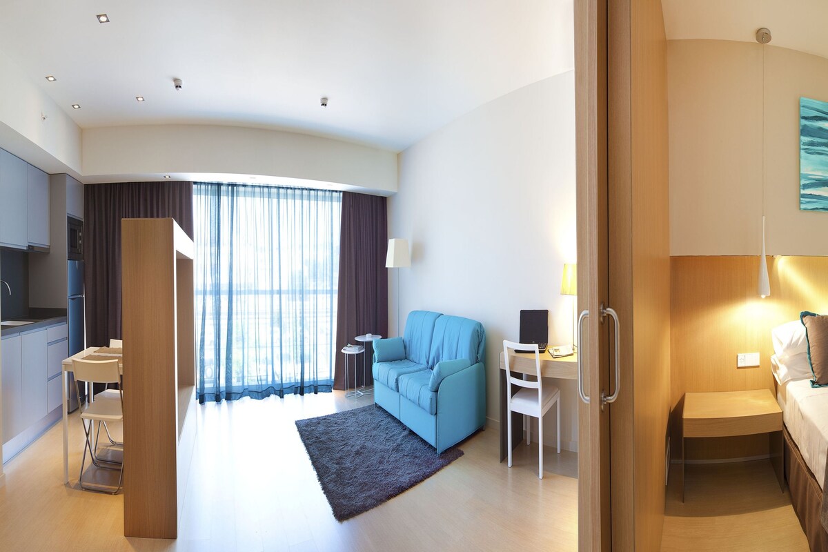 Une chambre d’hôtel avec un lit, un bureau, une chaise, un canapé et une vue sur la ville.