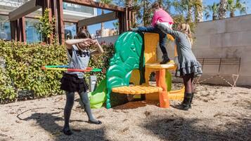 Kids can play on the slide and climbing wall in this outdoor play area surrounded by palm trees.