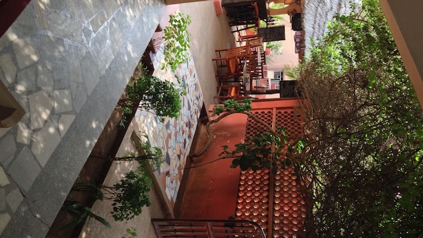 A courtyard with a tiled floor, a wooden bench, and a metal gate. - Napoléon Aéroport (Lomé)
