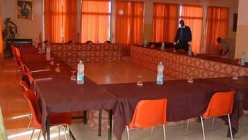 A conference room with a long table, orange chairs, and a patterned wall.