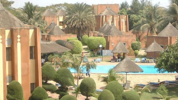 A resort with thatched-roof huts, a swimming pool, and well-maintained greenery.