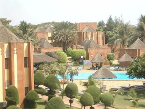 A resort with thatched-roof huts, a swimming pool, and well-maintained greenery. - Hôtel Mandé (Bamako)