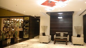 Un vestíbulo con suelo de mármol, un mostrador de recepción y dos sillones.