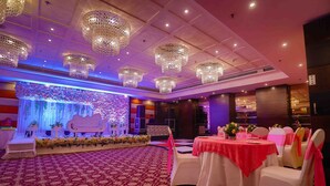 Un salón de banquetes con escenario, decoración floral y candelabros.
