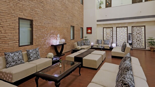 Un espacio habitable amplio con una pared de ladrillo, varios sofás y una mesa de centro de vidrio.