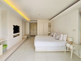 Un dormitorio moderno con una cama grande, un televisor en la pared y un vestidor.