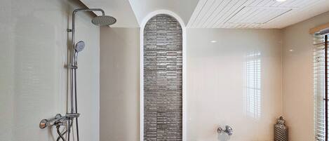 Un baño moderno con ducha, bañera y una pared decorada con piedra.