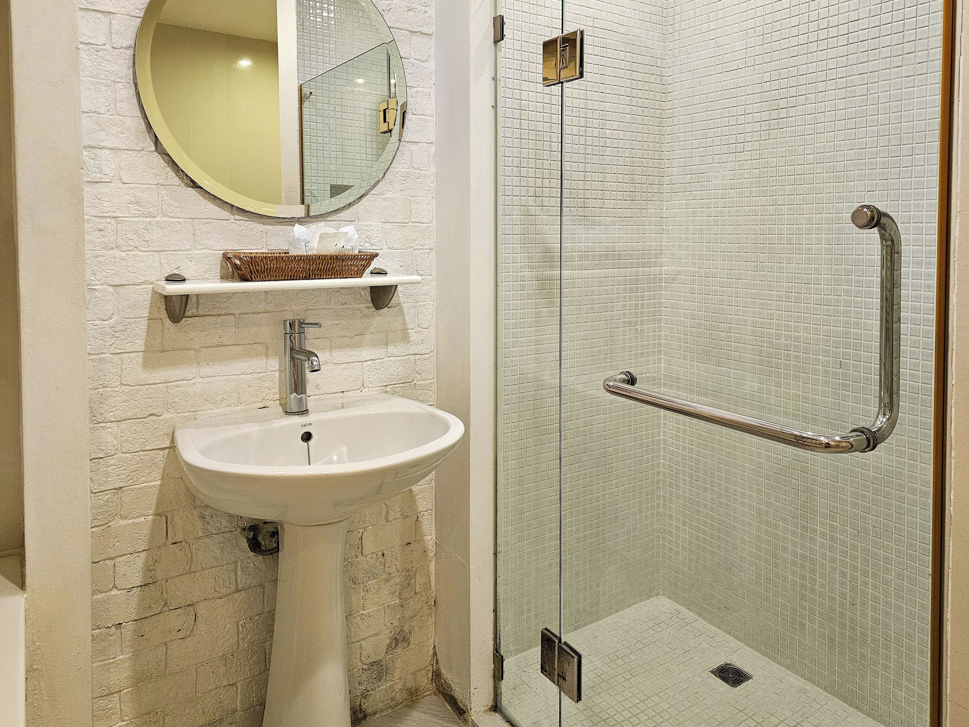 A bathroom with a white sink, a mirror, and a glass shower enclosure.