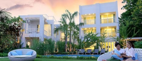 Relax in a serene atmosphere surrounded by lush tropical plants and trees, with two inviting outdoor seating areas.