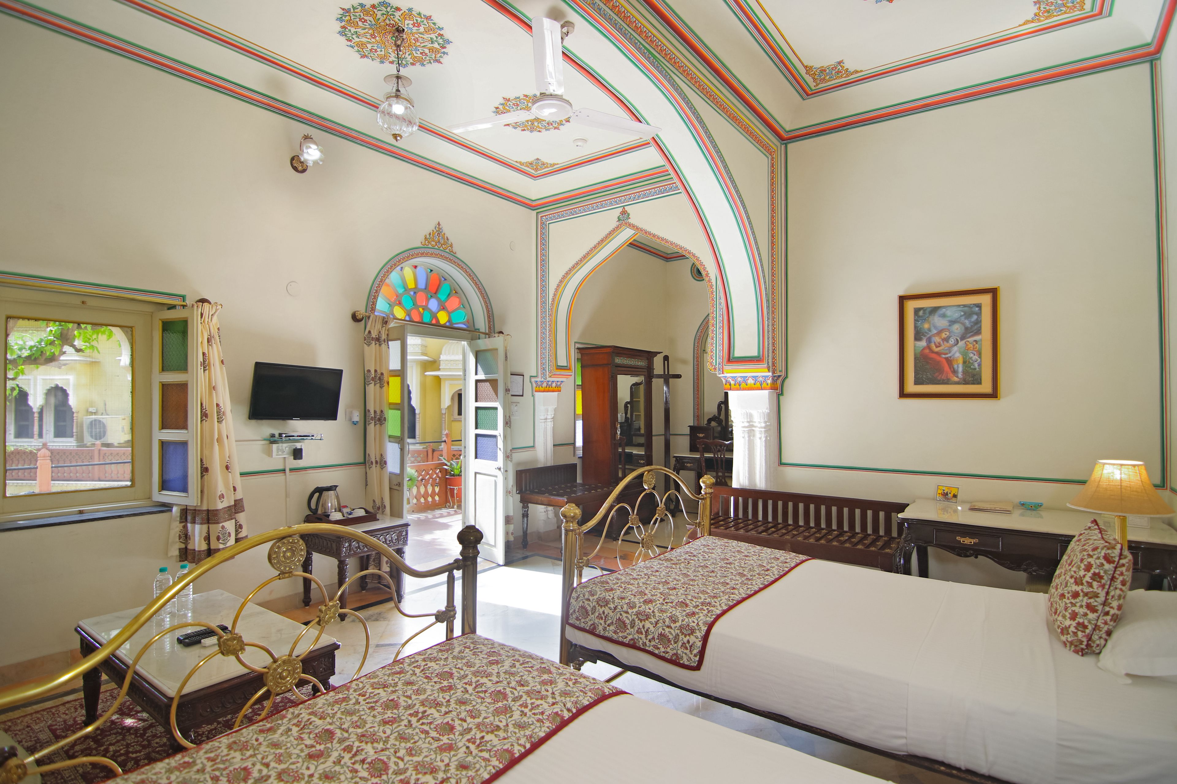 A hotel room with two beds, a television, a desk, and a window with curtains.