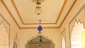 A corridor with arches, a chandelier, and a bench. - Alsisar Haveli - A Heritage Hotel (Jaipur)