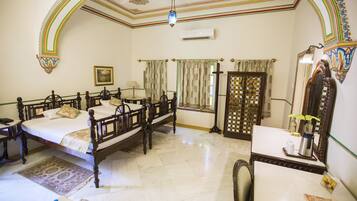 A room with two wooden beds, a desk with a chair, a mirror, and a window with curtains.
