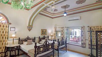 Una habitación tradicional con una cama, una mesa y un ventanal con cortinas.