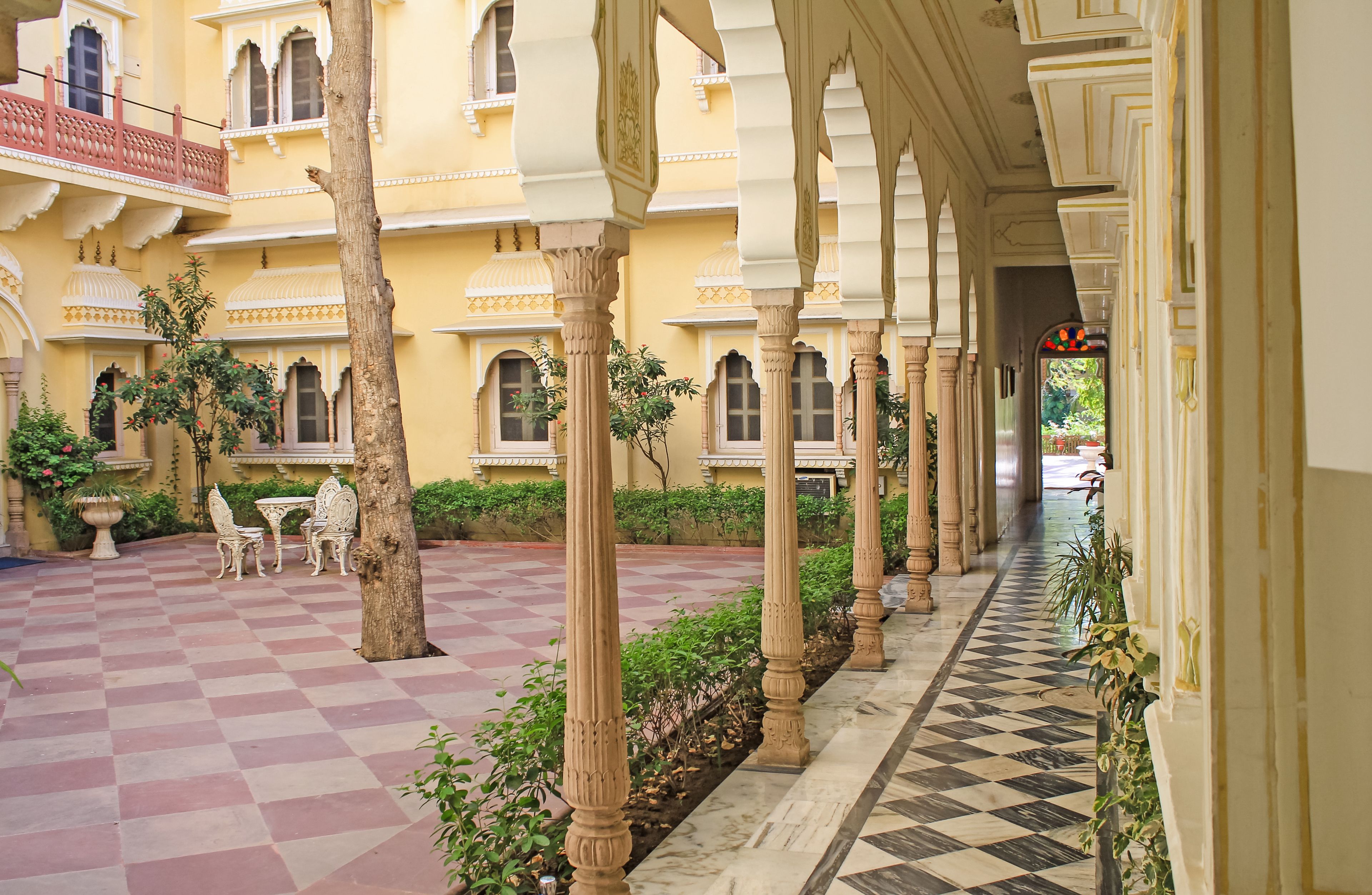 A courtyard with a checkered floor, columns, and a seating area with a table and chairs.