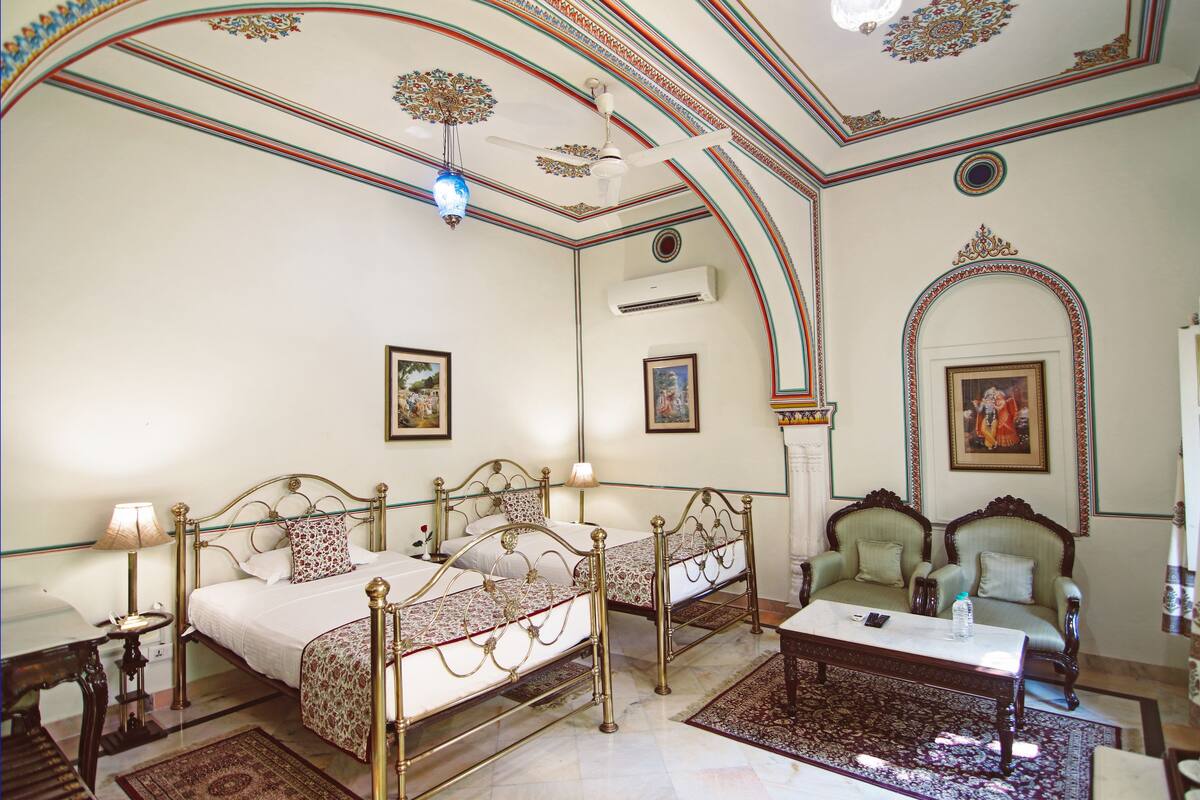 A traditional room with two beds, a sofa, and a table.