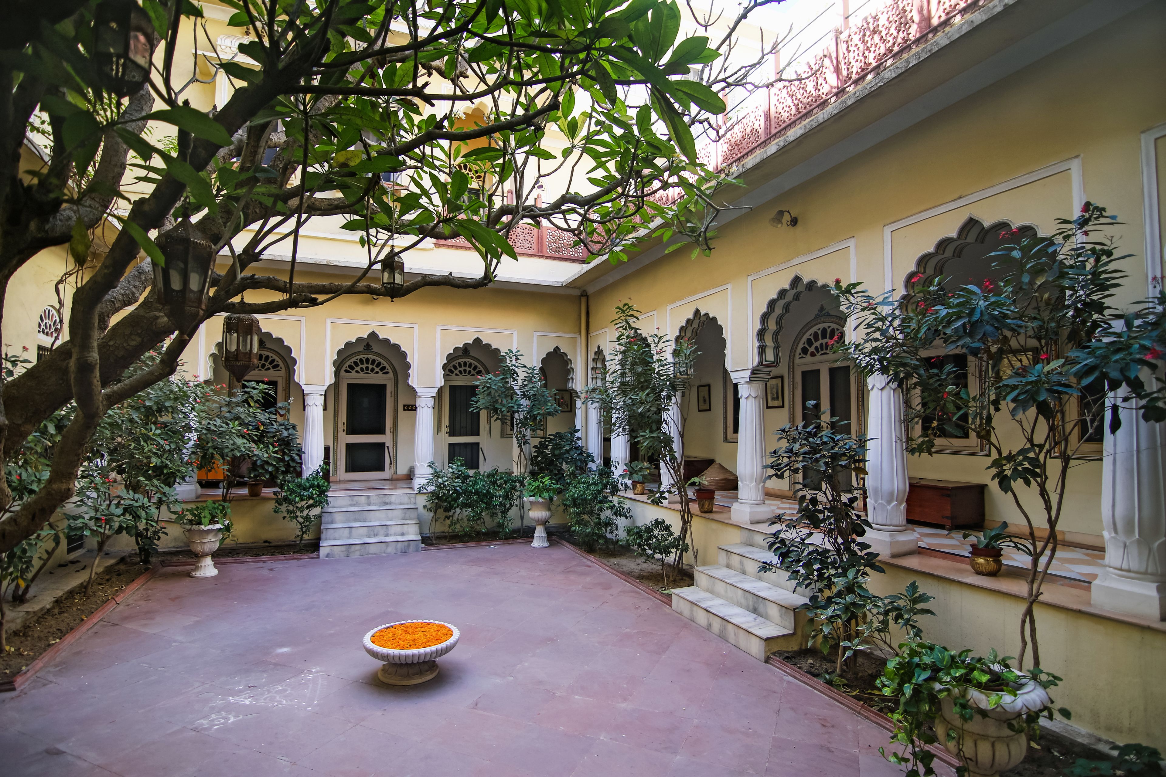 Un patio con una fuente central, plantas en macetas y elementos arquitectónicos tradicionales.