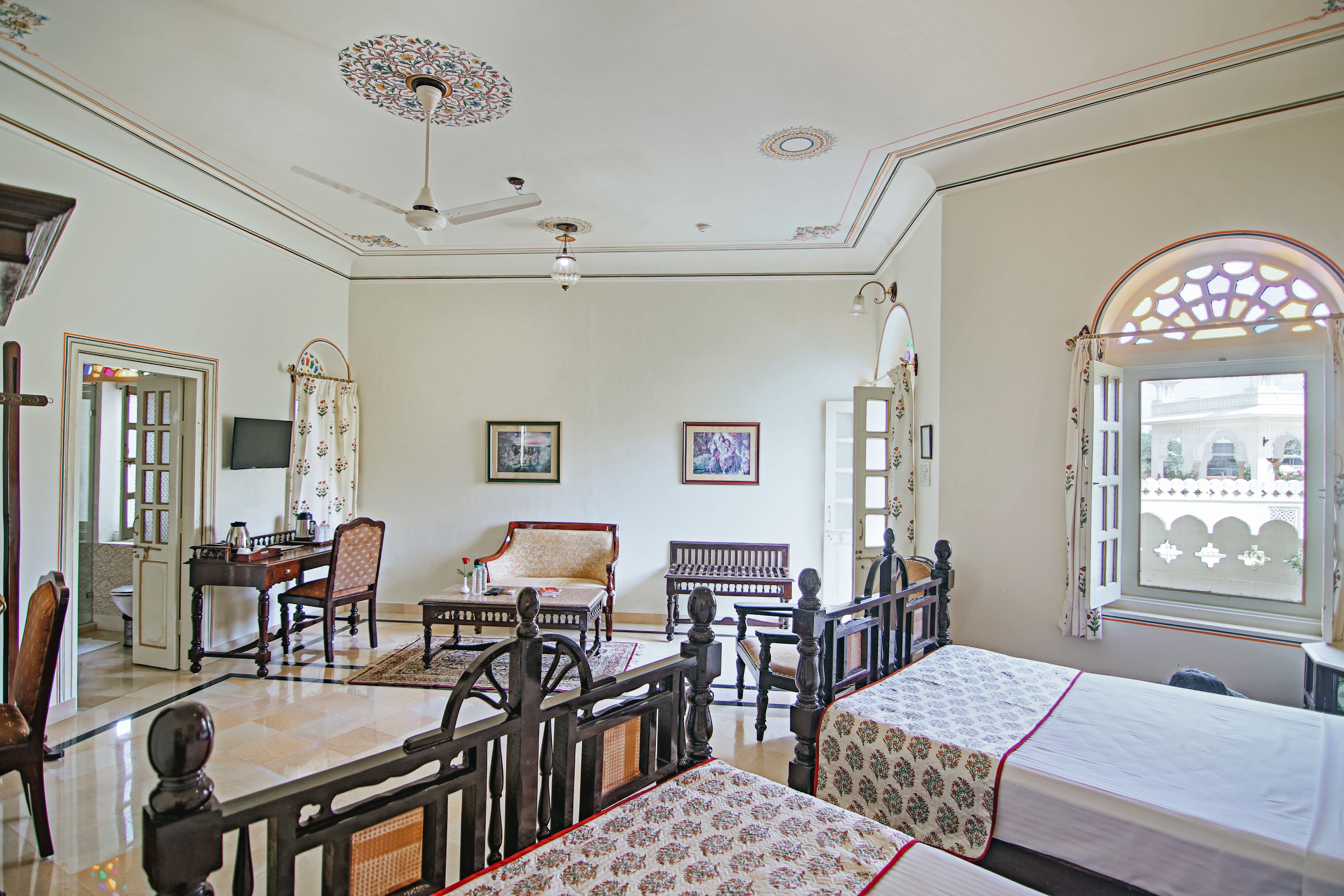 Una habitación tradicional con cama, escritorio, silla y televisión.