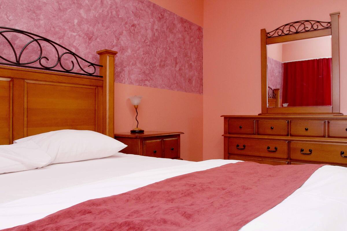 A bedroom with a wooden bed, a dresser, and a mirror.