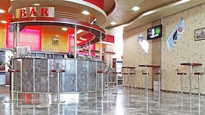 A bar area with a marble counter, multiple stools, and a television screen mounted on the wall. - Hotel BM International (Sarajevo)