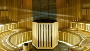 A sauna with wooden benches and a central pillar, surrounded by warm lighting. - Hotel BM International (Sarajevo)