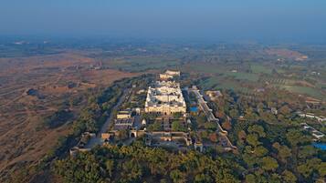 An aerial view of a large, historic building complex surrounded by dense forest and fields.