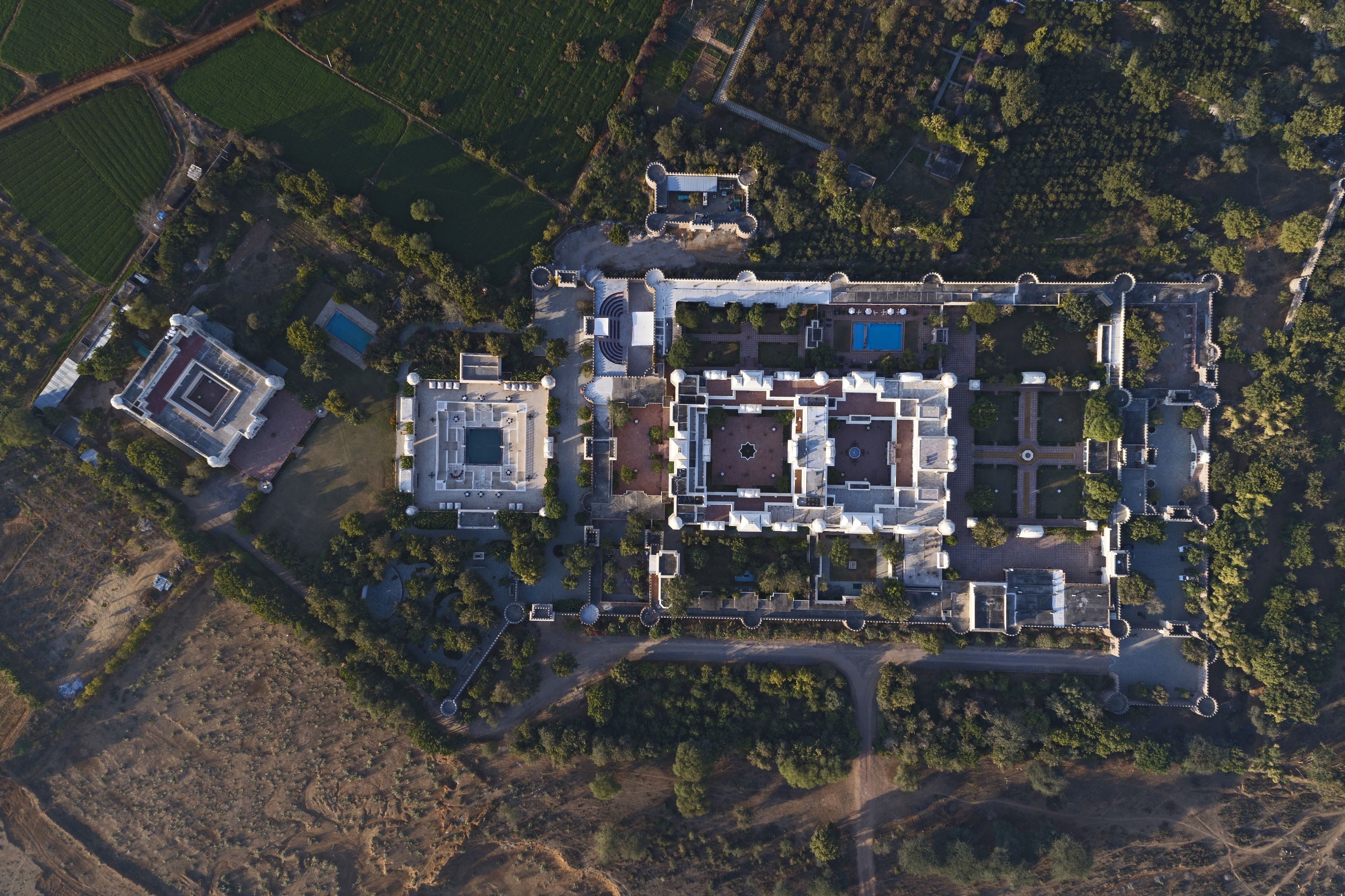 An aerial view of a large estate with a central courtyard, multiple buildings, and surrounding greenery.