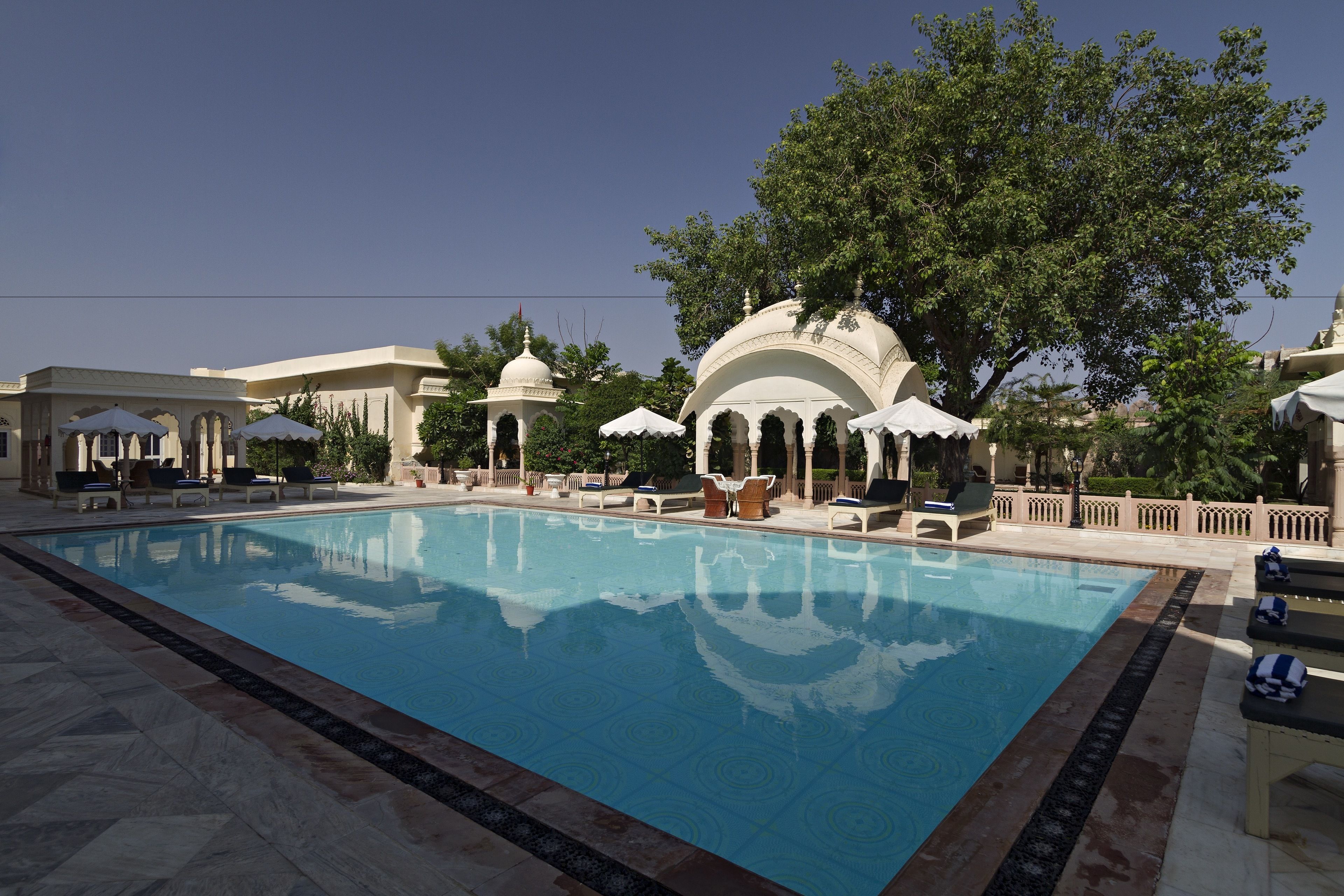 Een buitenzwembad, ligstoelen bij het zwembad