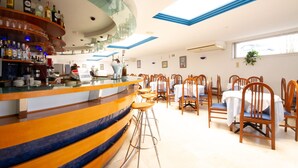 A bar area with a curved counter, multiple stools, and a seating area with tables and chairs.