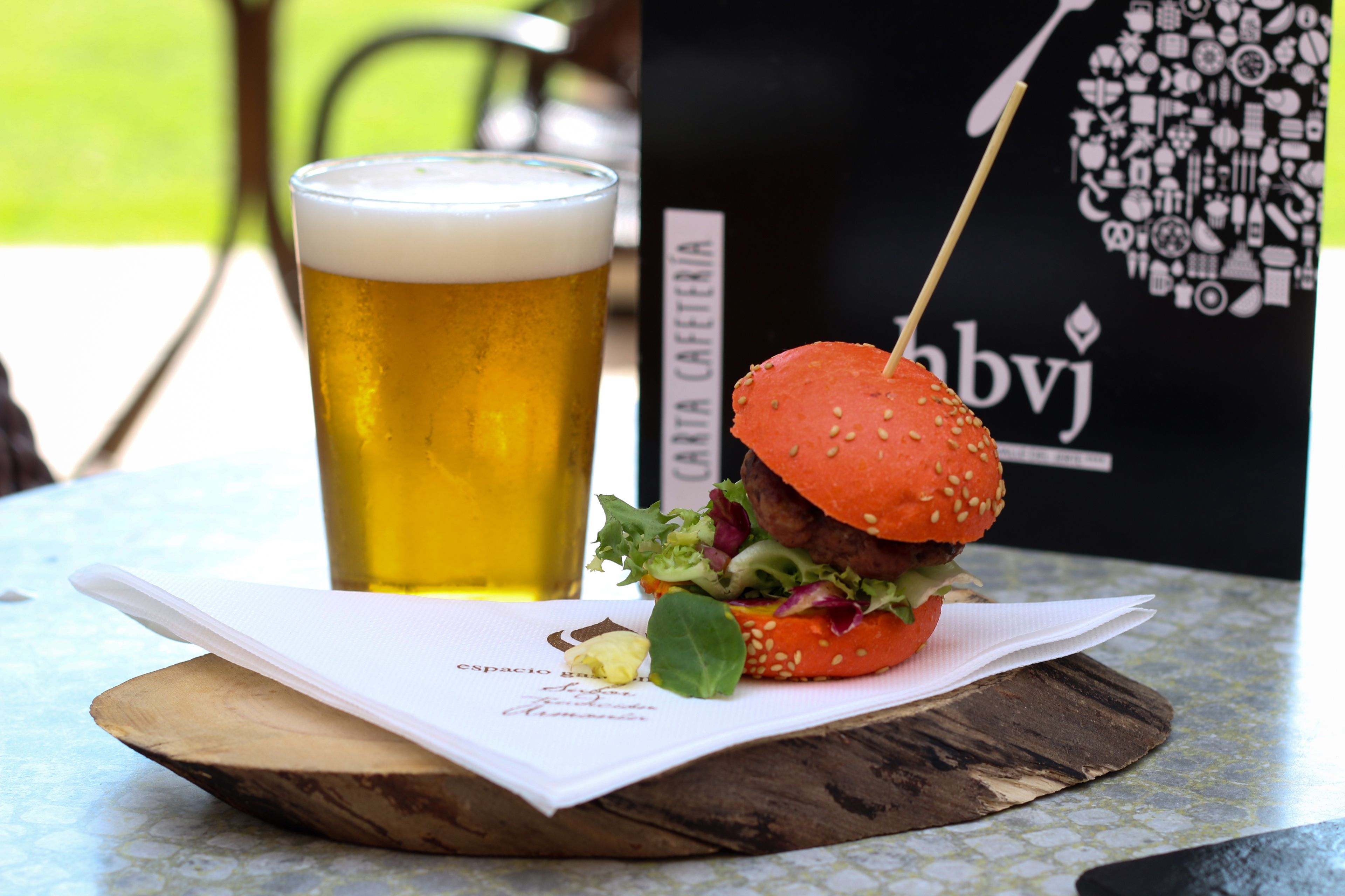 Een maaltijd bestaande uit een hamburger en een glas bier op een tafel met een menukaart.