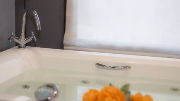 A bathtub with a chrome faucet and a glass panel.