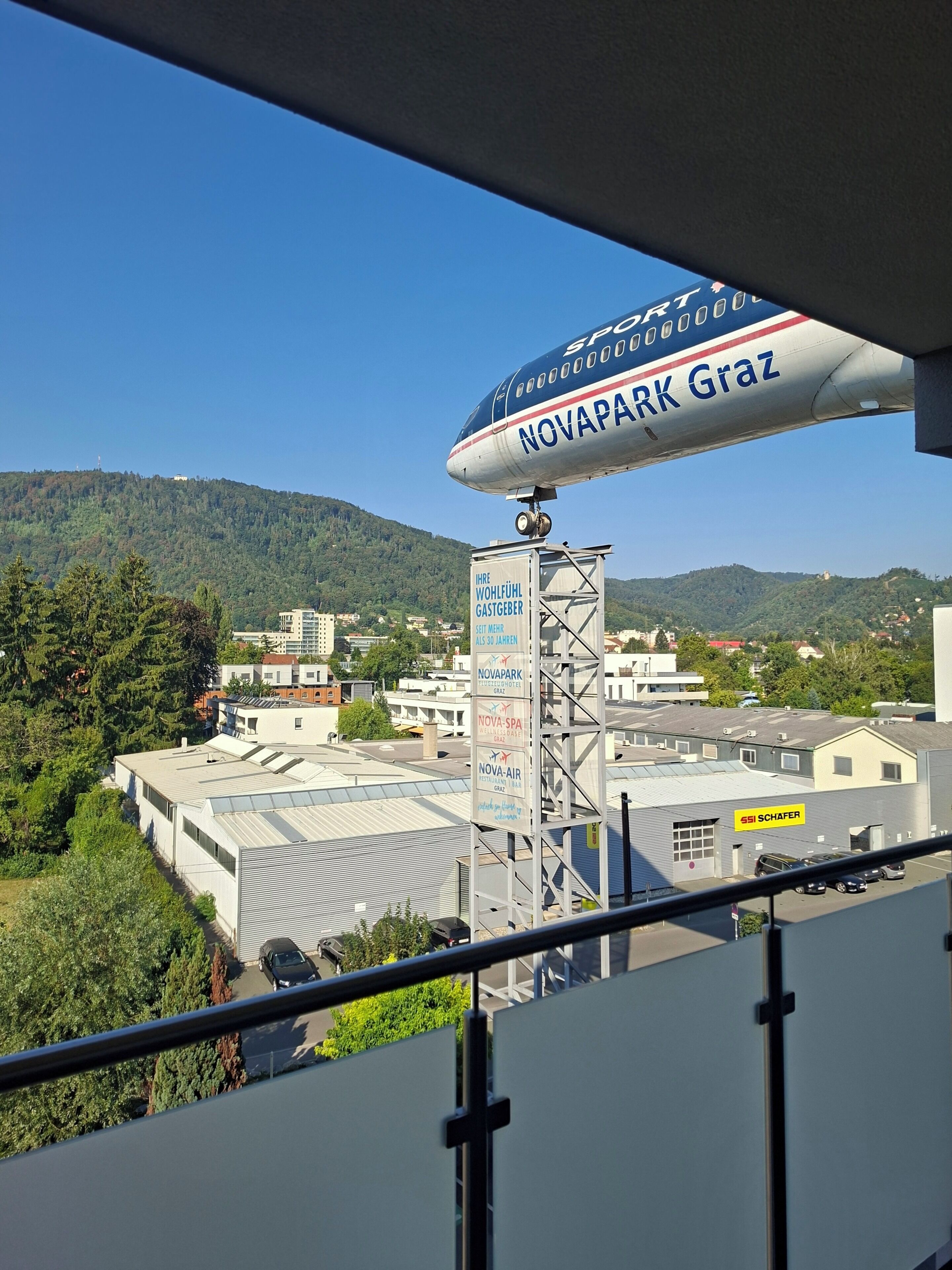 A Novapark Graz sign, a mountainous landscape, and buildings in the background.