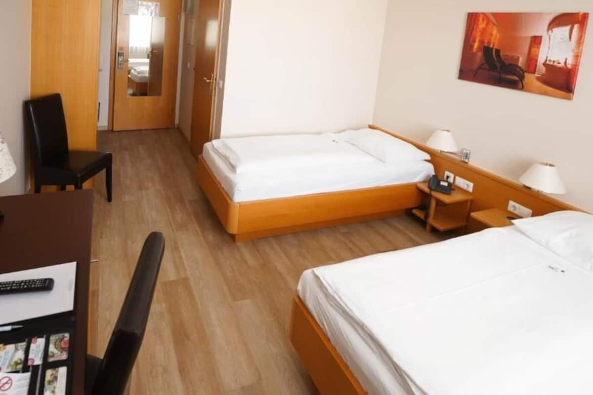 Una habitación de hotel con dos camas, un escritorio, una silla y un armario.