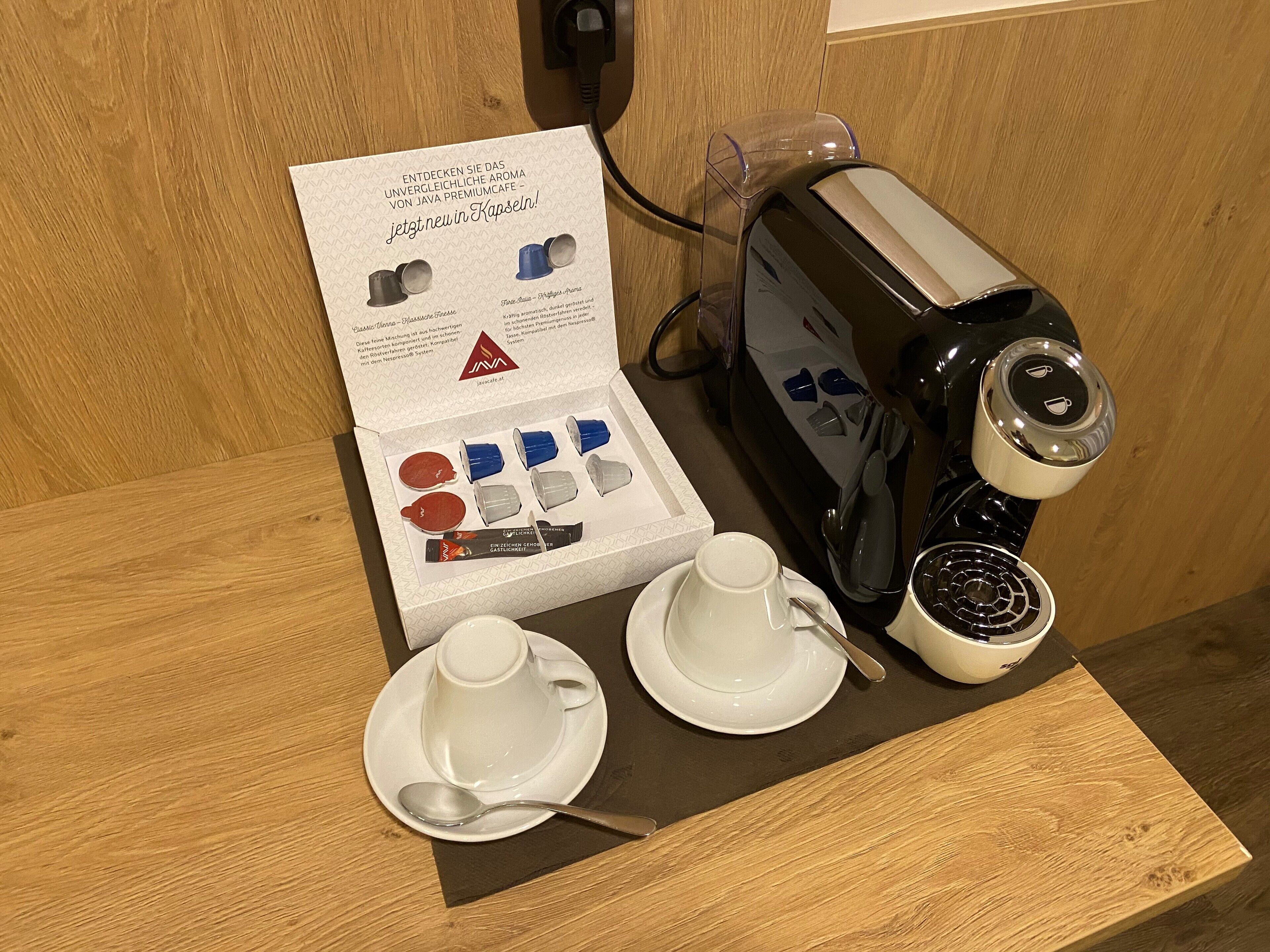 A coffee machine with a cup and saucer, a spoon, and a box of coffee cups.