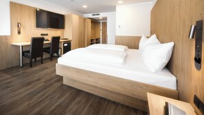 A modern hotel room with a large bed, a desk, and a flat-screen TV. - Novapark Das Flugzeughotel (Graz)